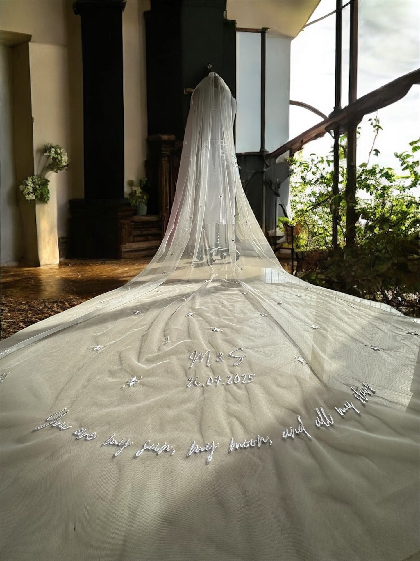 Long white wedding veil with embroidered text in an indoor setting