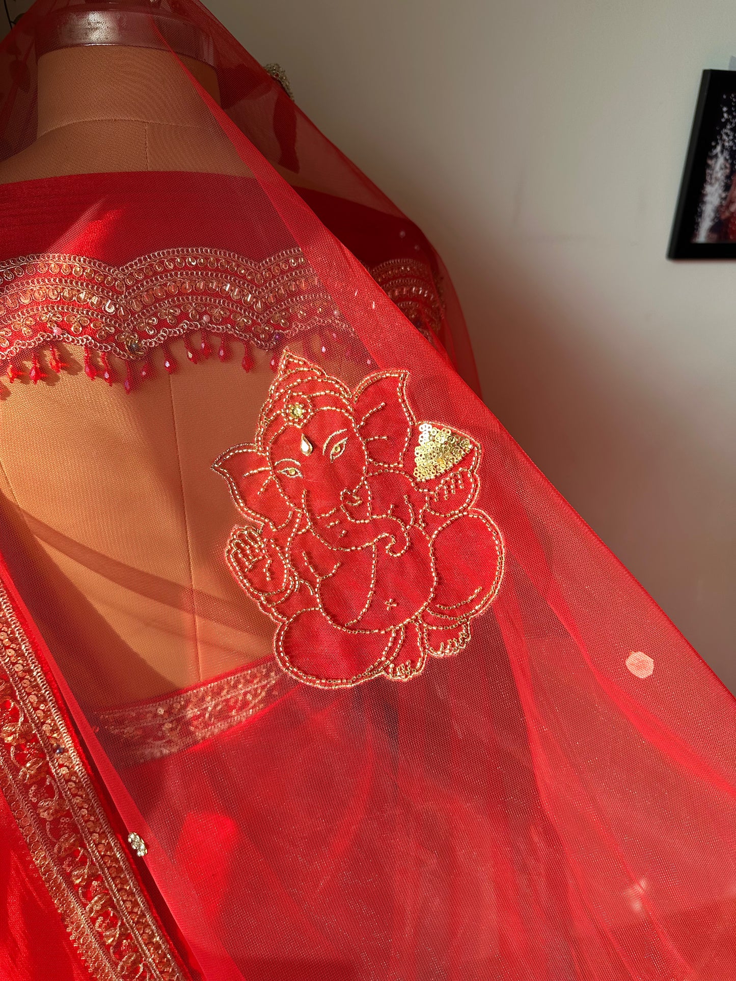 Niyati : A red cathedral length with hand beaded Ganesha on back