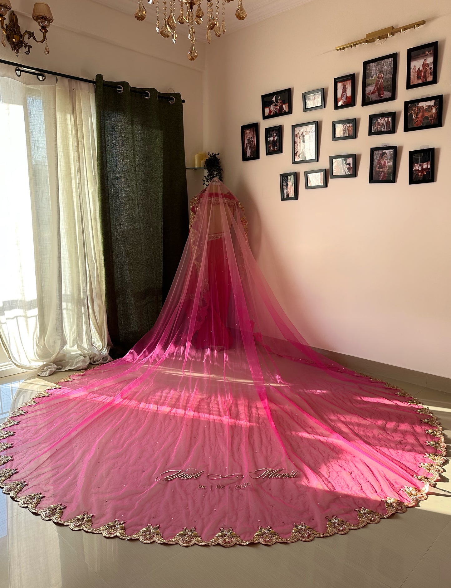 Pink long Veil with gold border on a mannequin in a room with decorative wall art.